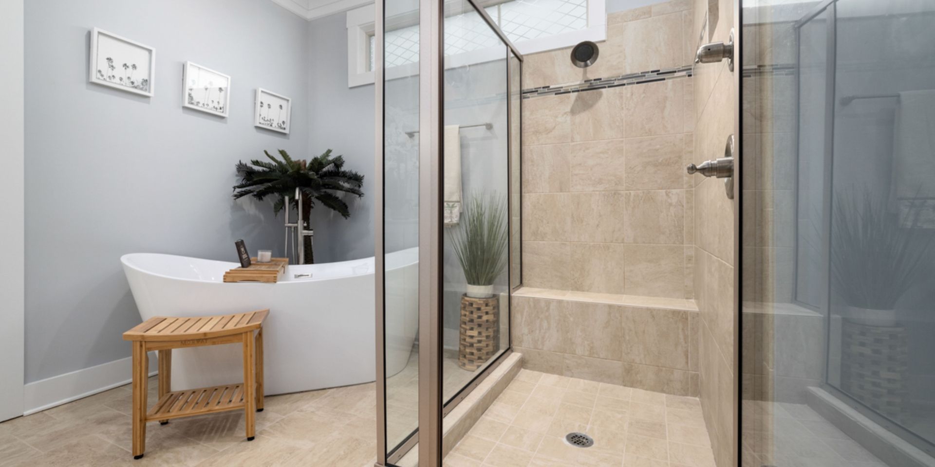 Bathroom with a bathtub, shower, and wood stool. Light gray walls, white tub, and beige tile.