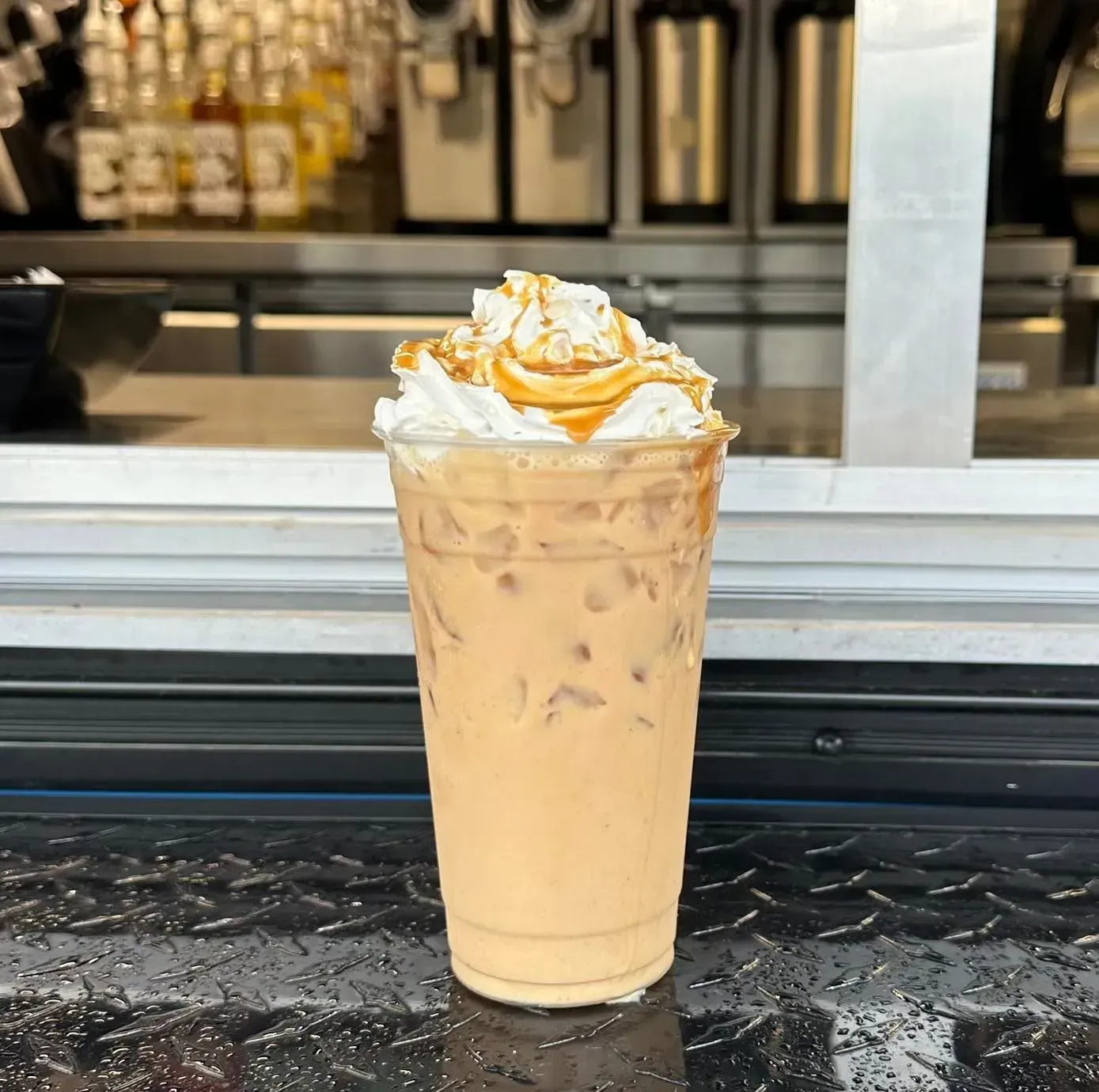 Iced caramel latte topped with whipped cream on a café counter