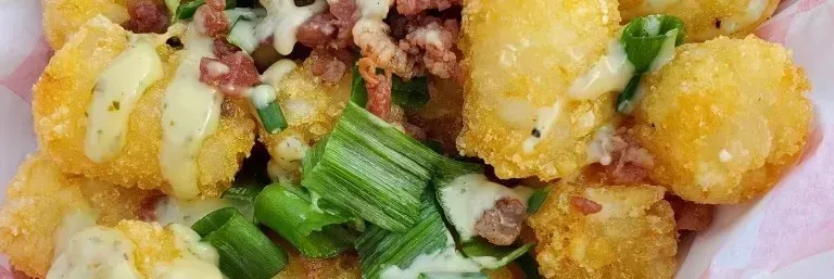 Close-up of golden fried dumplings with green onions and bits of bacon on a plate