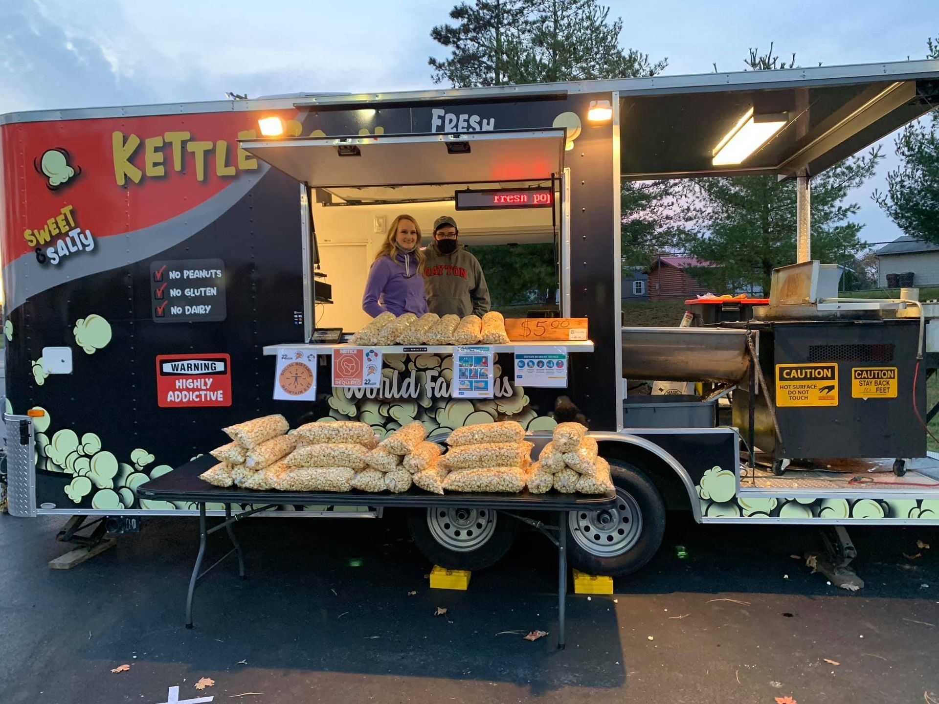 Food truck called “Kettle” with pastries displayed and two staff standing inside at dusk