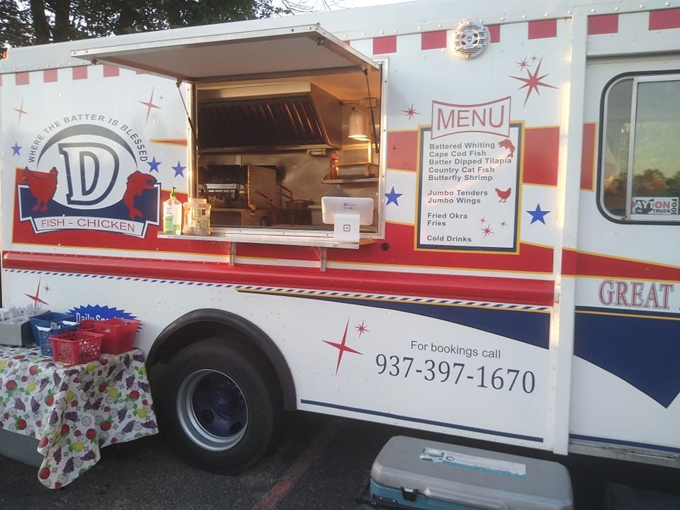 Food truck with open service window, menu board, and red-white-blue stars parked outdoors.