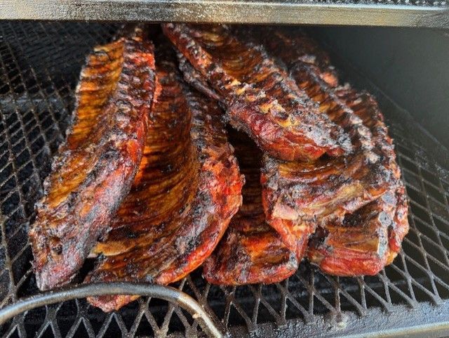 Smoked barbecue ribs stacked on a grill, browned and glazed with sauce