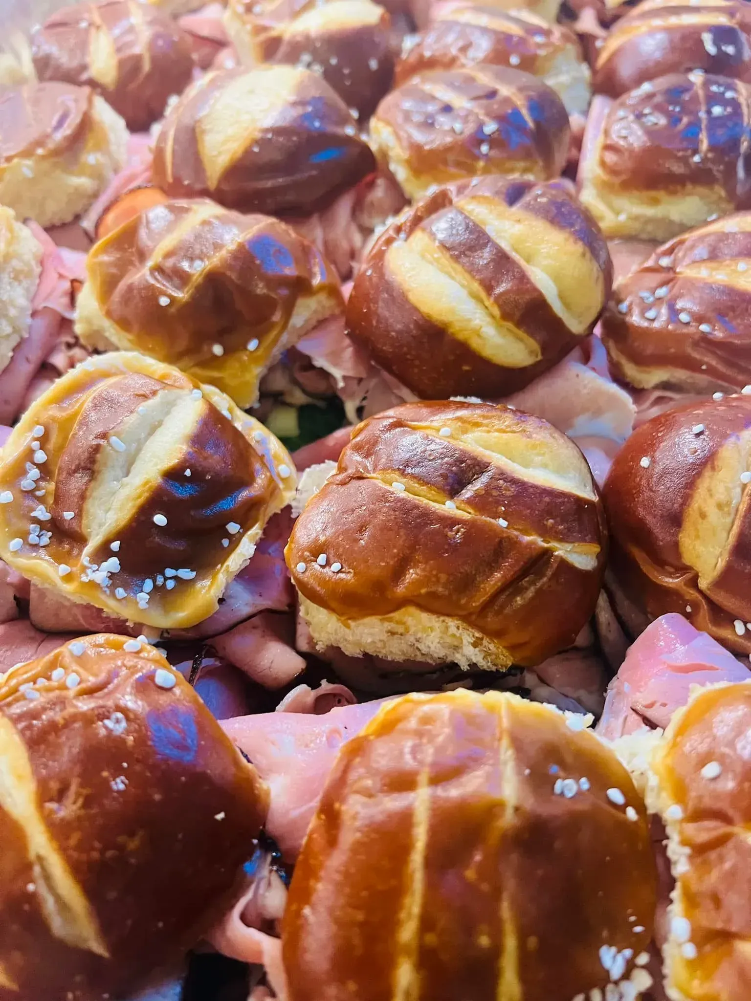 Tray of glossy baked pretzels with white icing drizzle and coarse salt pieces