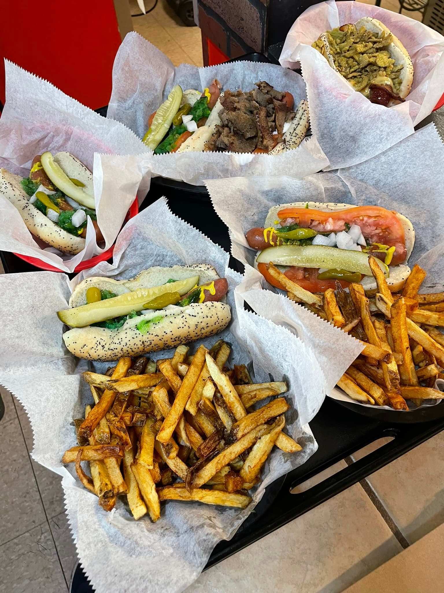 Basket of sandwiches and fries on a table, with one bowl of salad and another side dish.