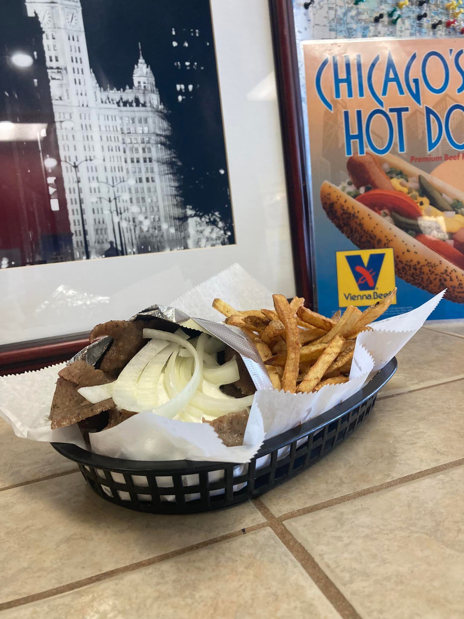 Basket of Chicago-style hot dogs and fries on a table inside a restaurant.