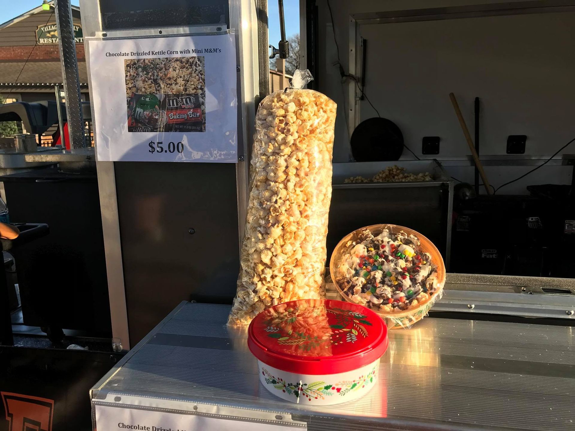 Popcorn stand with tall clear tub, red bowl, and round snack display on a counter