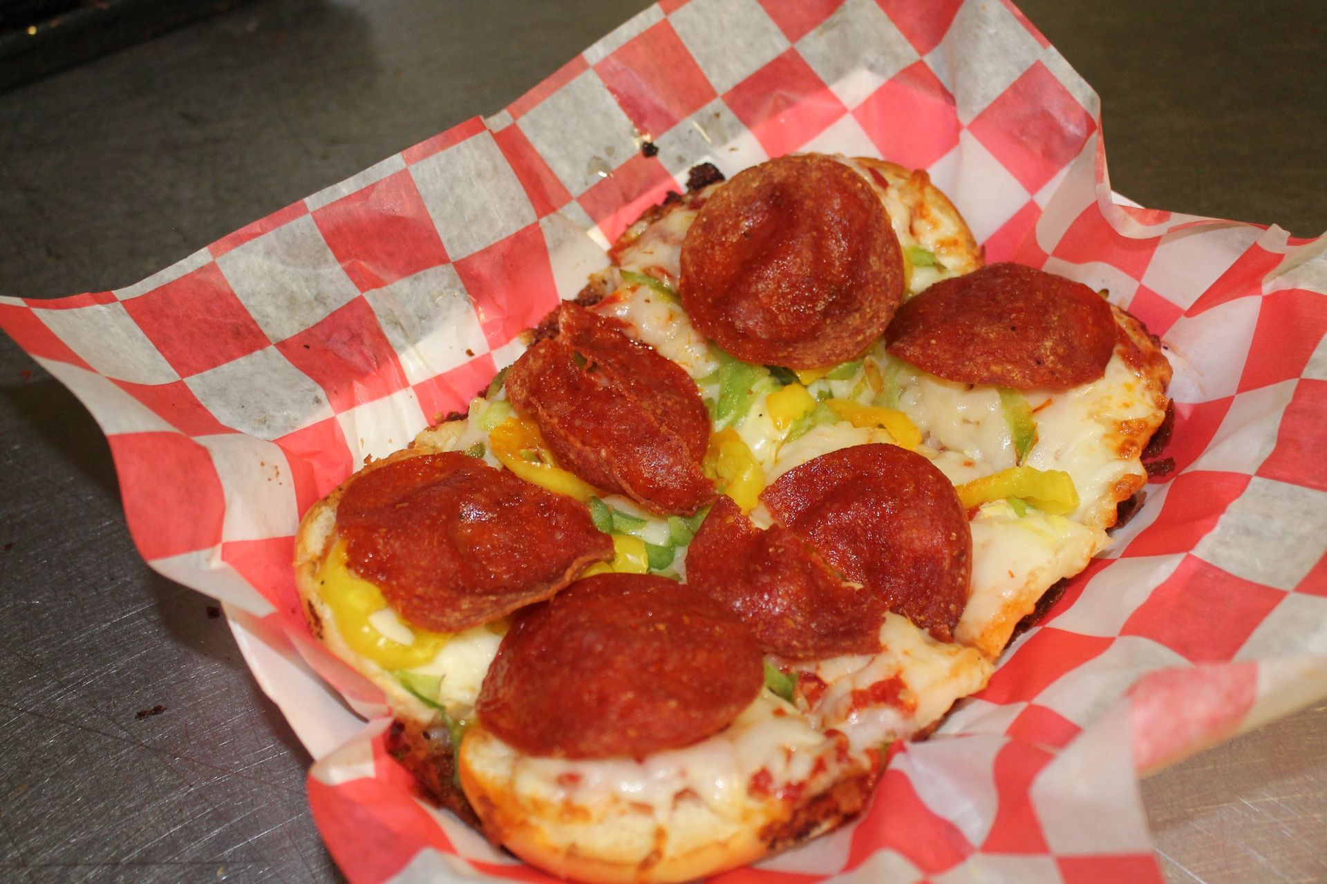 Pepperoni pizza slice in a red-and-white checkered paper tray