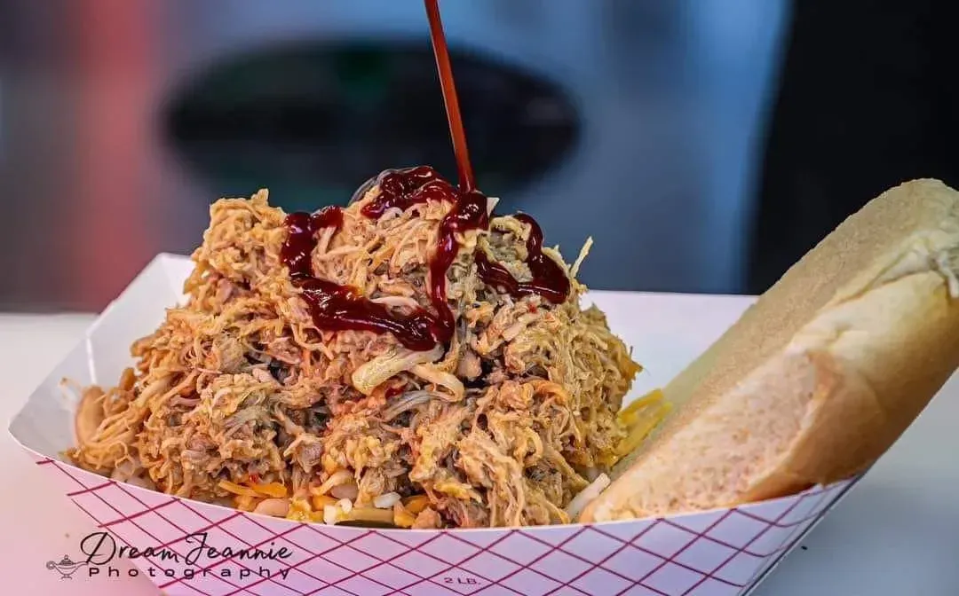 Large serving of saucy noodles with a breadstick on a tray