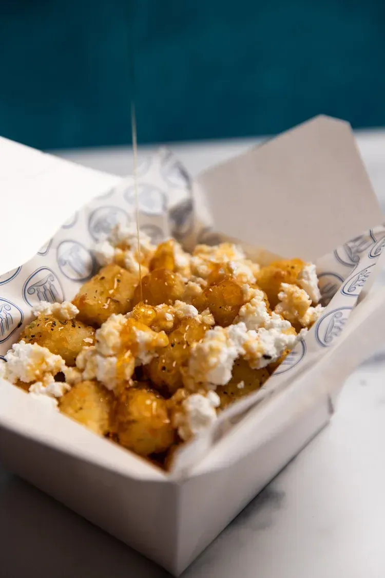 A paper tray of powdered sugar-topped fried dough bites on a table