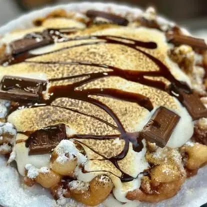 Dessert topped with whipped cream, chocolate drizzle, and chocolate pieces