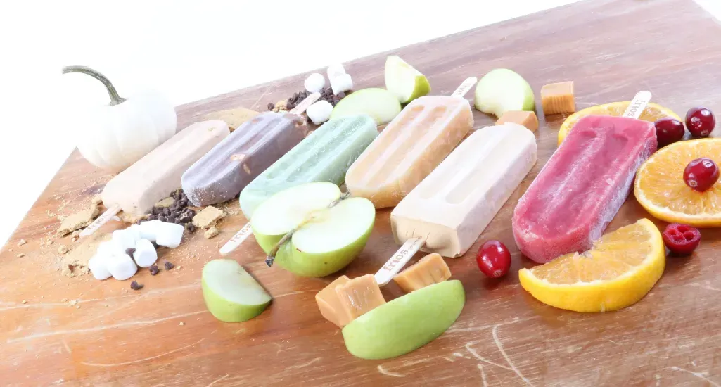Assorted colorful popsicles and fruit ice pops on a wooden board, with orange and grapefruit slices