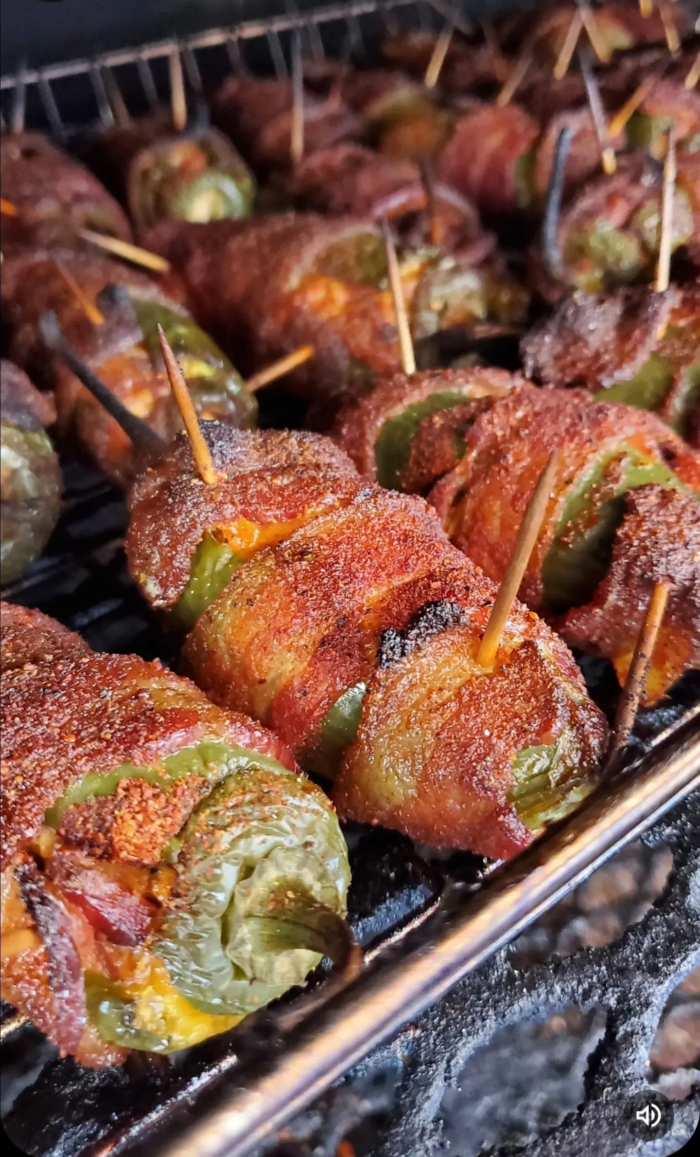 Skewered bacon-wrapped peppers grilling on a wire rack, browned and crispy.