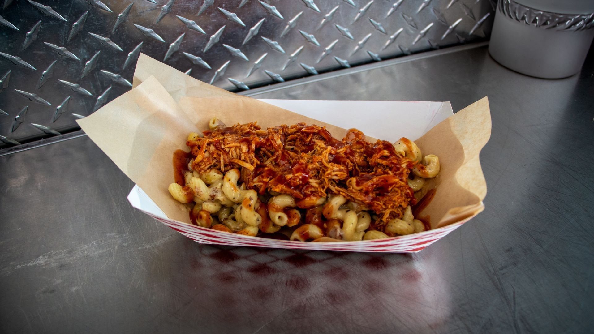 Red-sauced loaded fries in a paper-lined basket on a metal table