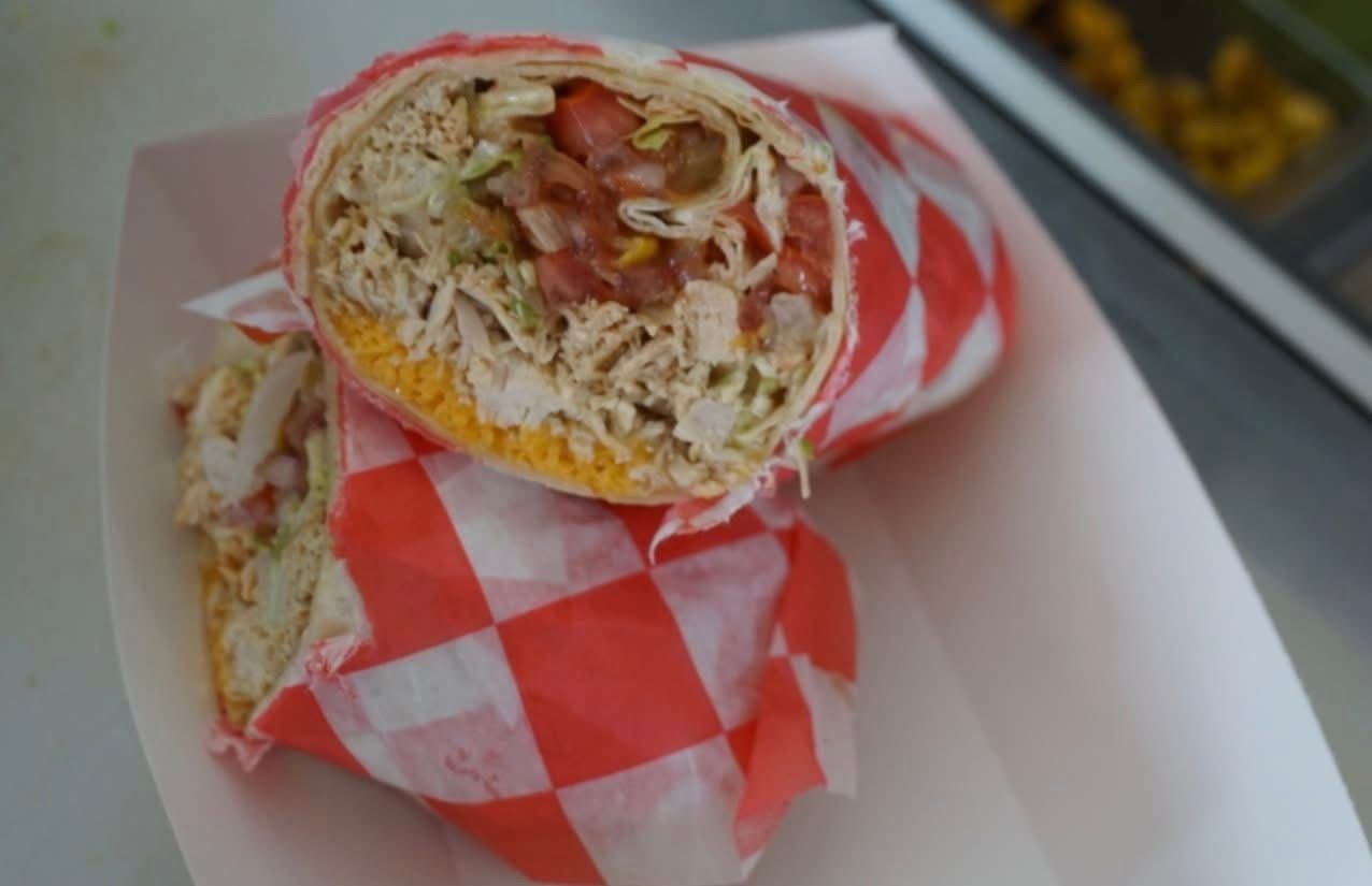 Wrapped burrito cut in half on a tray with red-and-white checkered paper.