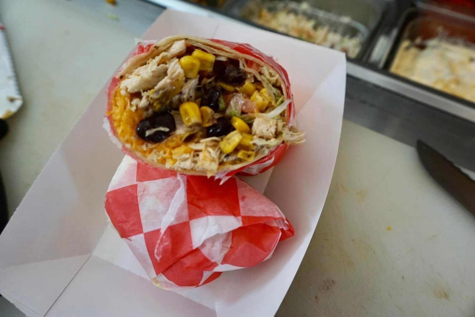Close-up of a burrito bowl in a red-and-white checkered wrapper on a counter
