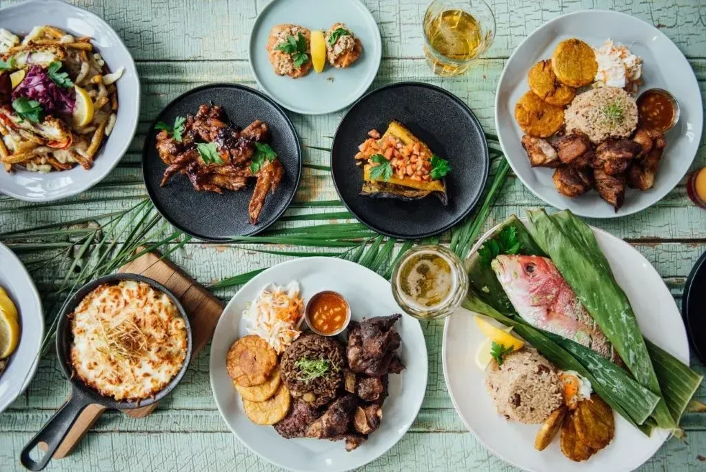 Assorted plated dishes and drinks arranged on a green table in an overhead dining spread