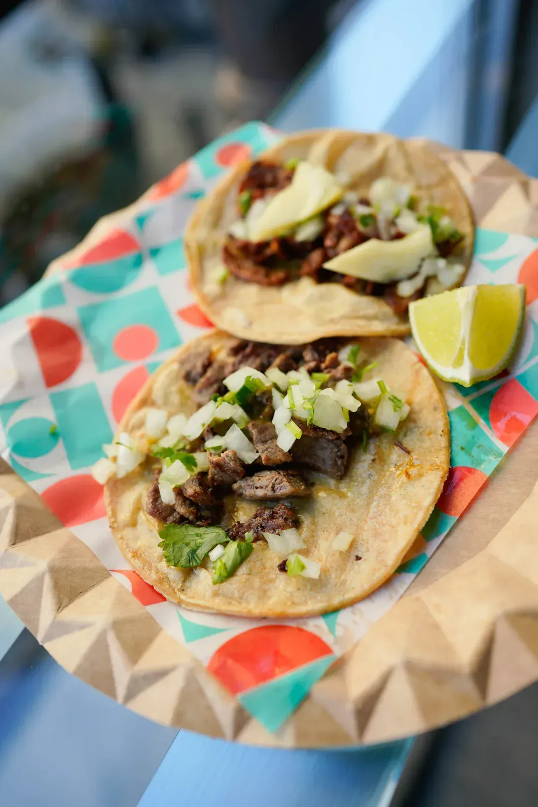 Two tacos on a patterned paper plate with a lime wedge