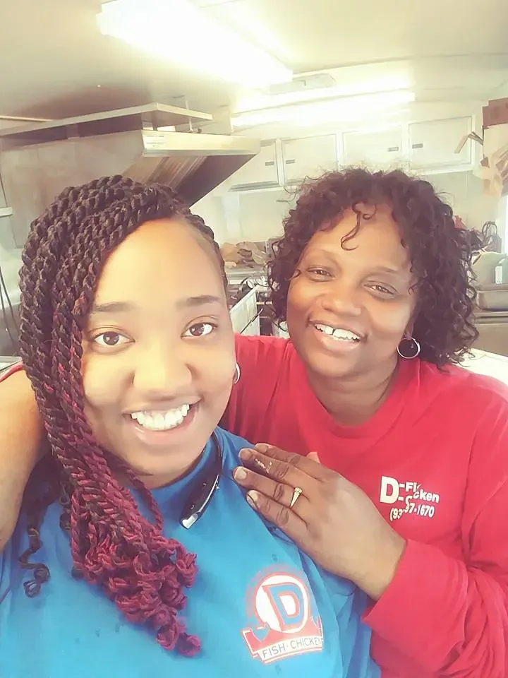 Two smiling women in red and blue shirts taking a selfie indoors