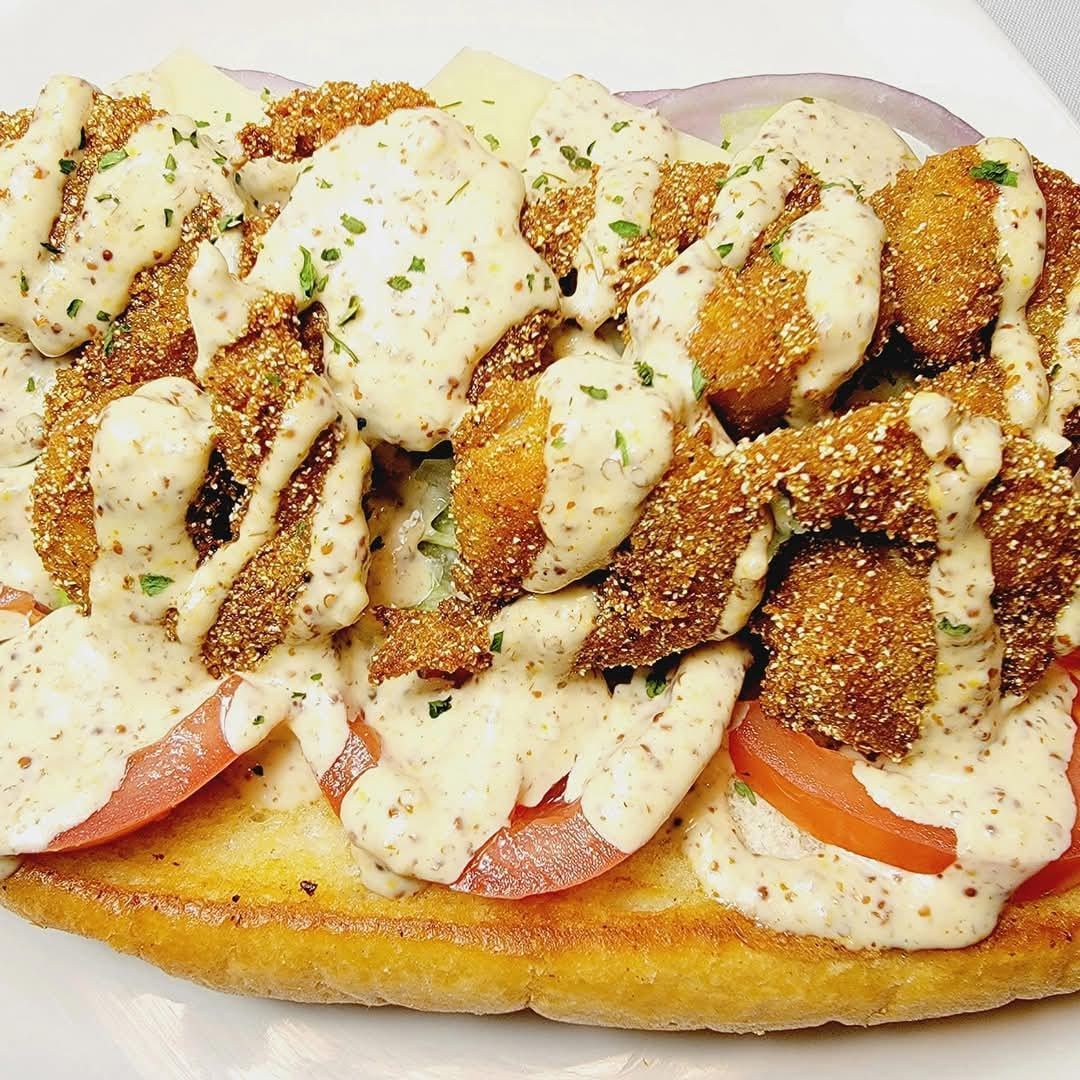 Open-faced sandwich topped with chicken, creamy sauce, and herbs on toasted bread