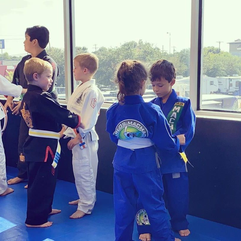 a group of young boys in martial arts uniforms are standing in front of a window