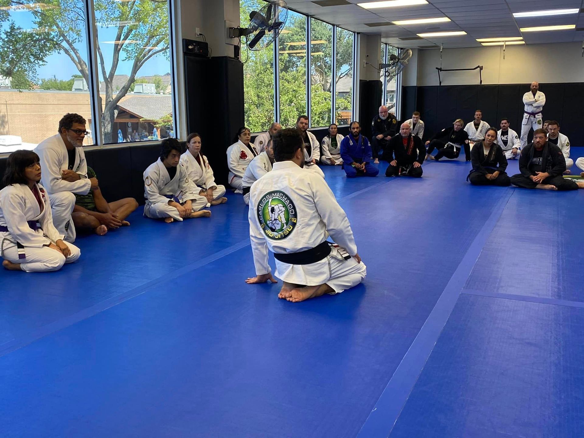 a group of people are sitting on a blue mat in a gym .
