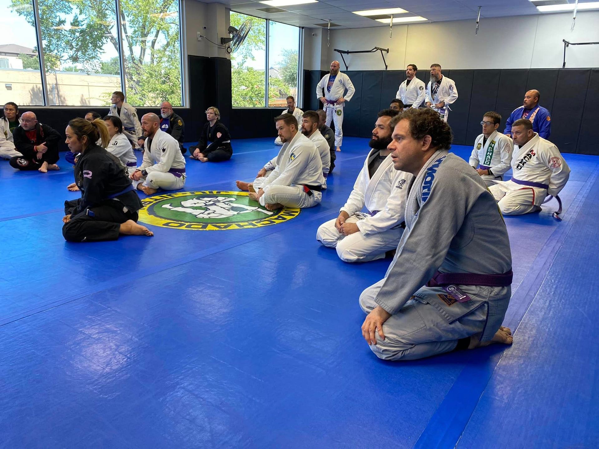 a group of people are sitting on a blue mat in a gym .