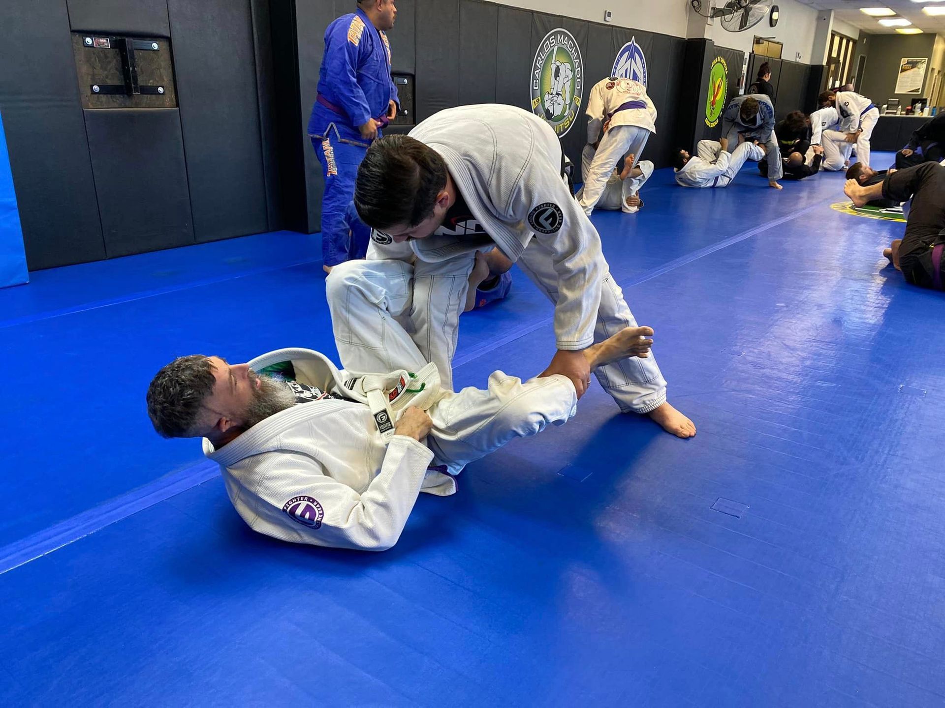 a group of people are practicing martial arts on a blue mat in a gym .