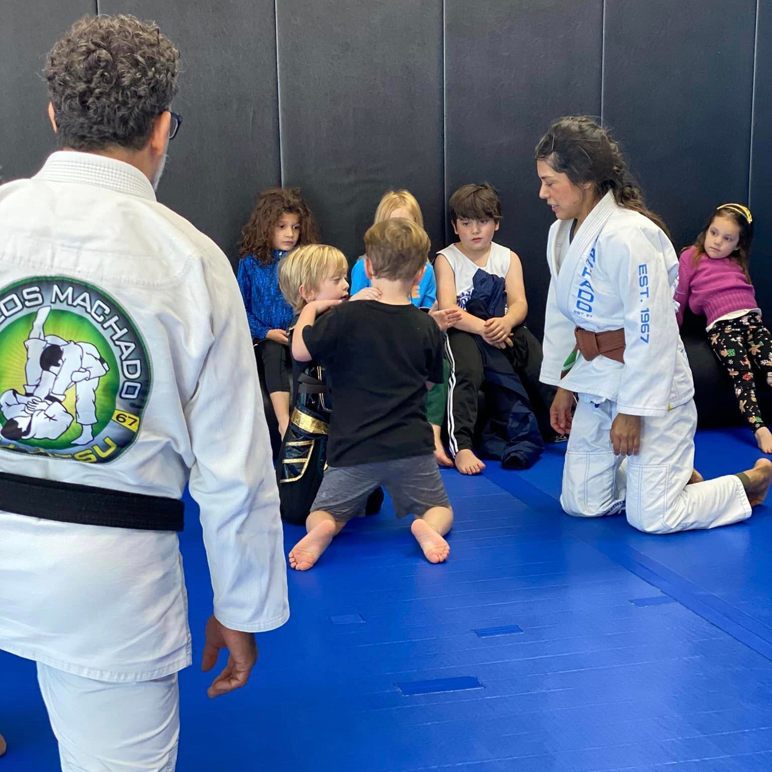 a man in a white karate uniform is standing in front of a group of children