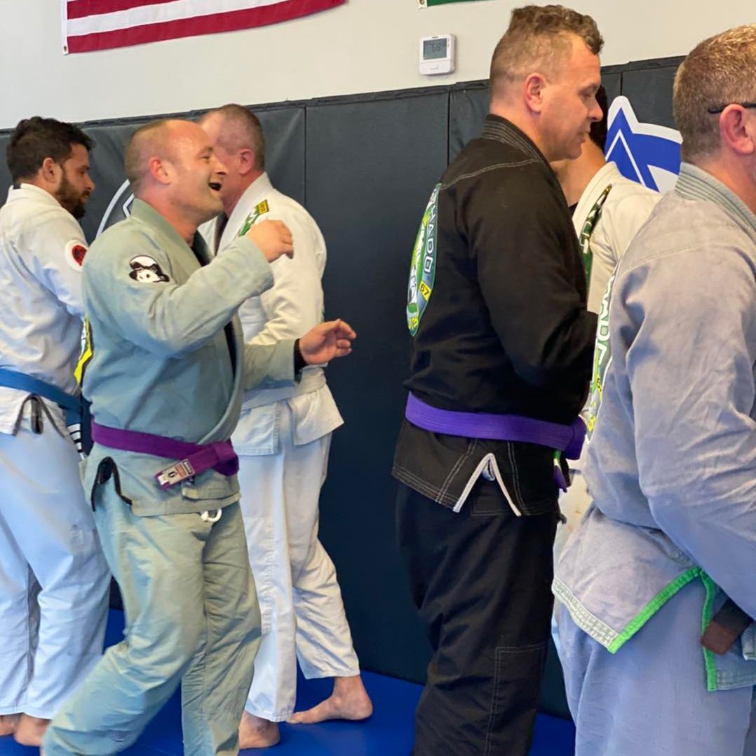 a group of men are practicing martial arts on a blue mat .