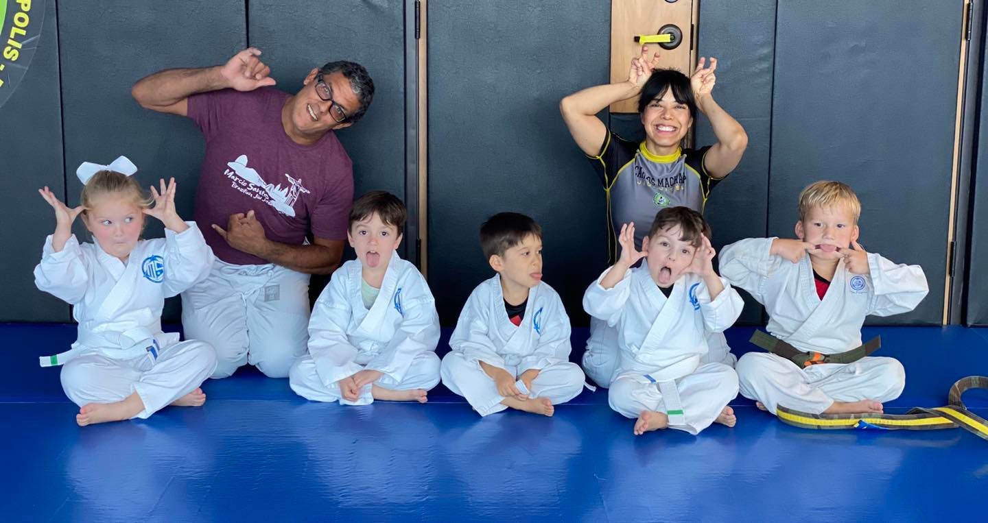 three children in karate uniforms are standing next to each other on a blue mat.