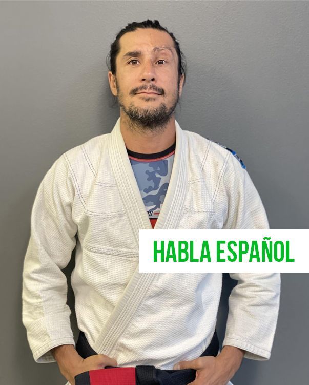 a man in a white karate uniform is standing in front of a sign that says habla espanol
