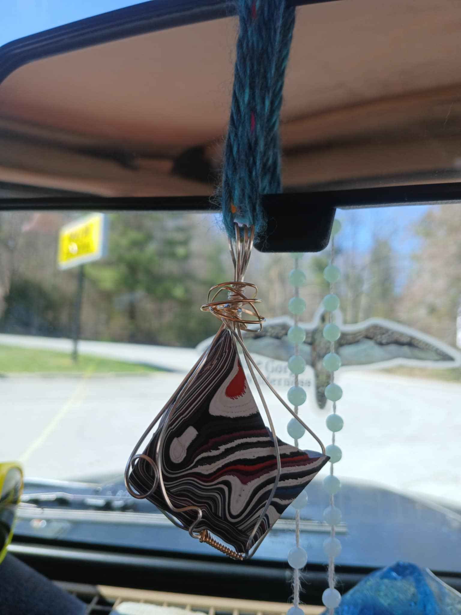 A car rear view mirror with a pendant hanging from it
