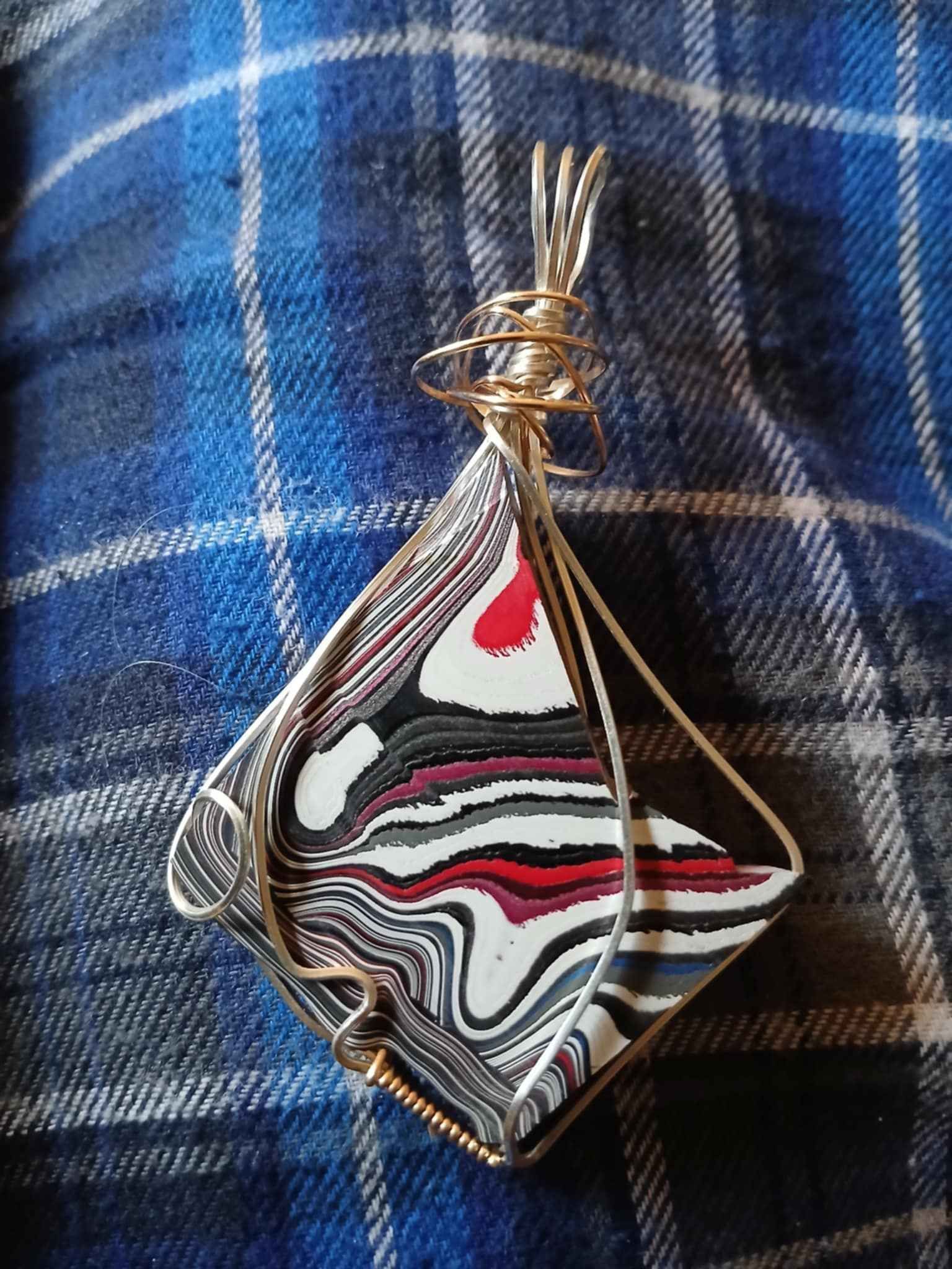 A pendant is sitting on top of a blue plaid blanket.