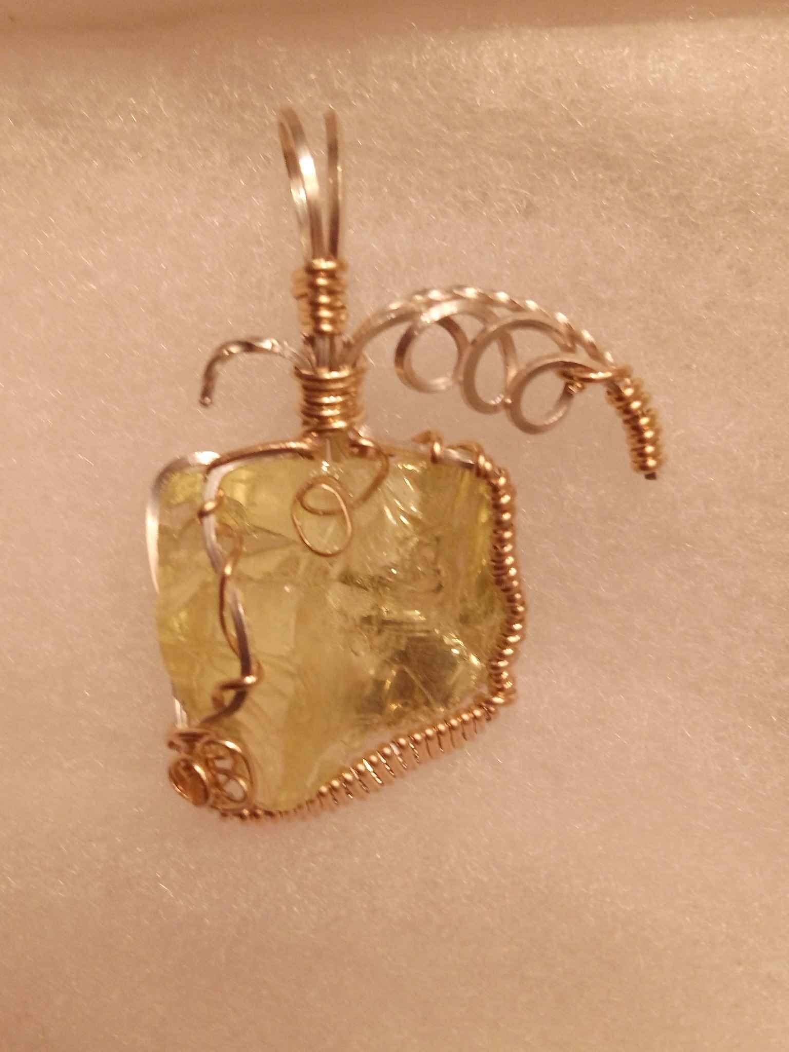 A close up of a wire wrapped pendant on a white surface
