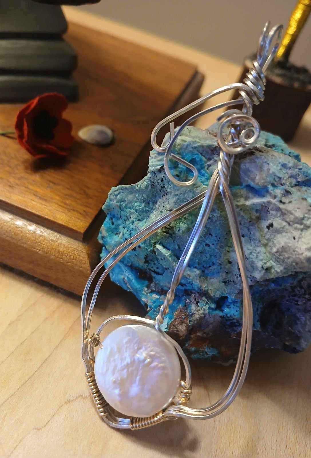 A wire wrapped pendant is sitting on top of a blue rock.