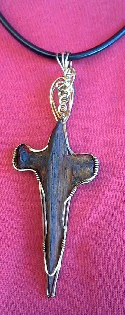 A close up of a necklace with a cross pendant on a pink cloth.