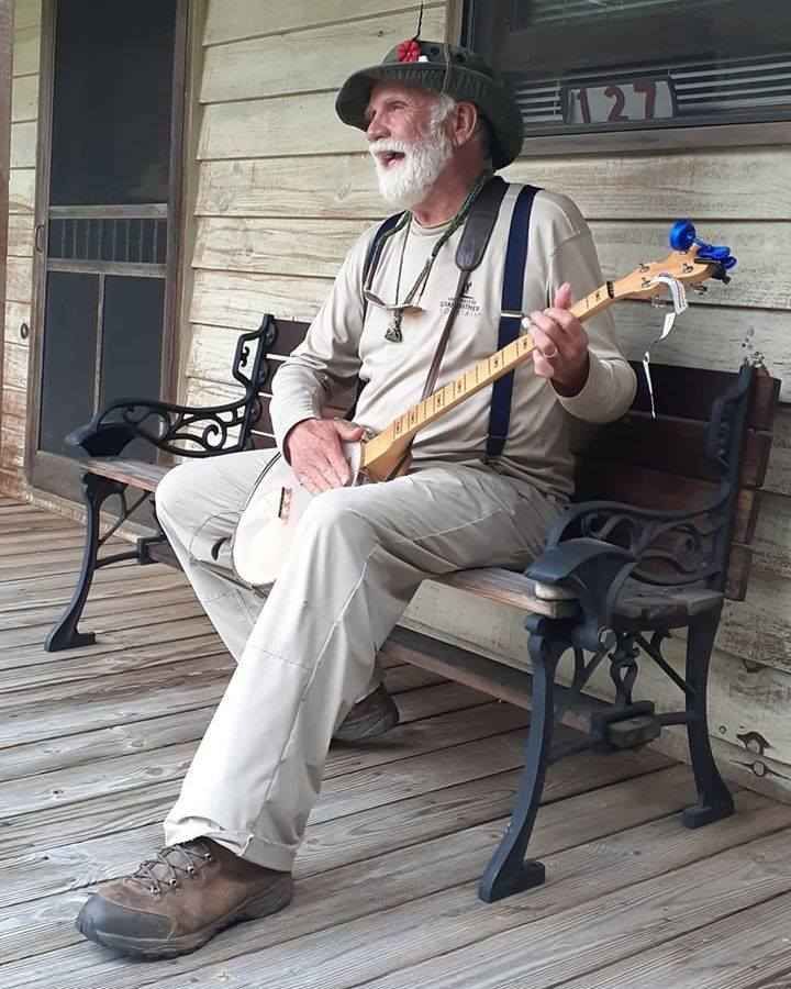 A man is sitting on a bench playing a banjo.