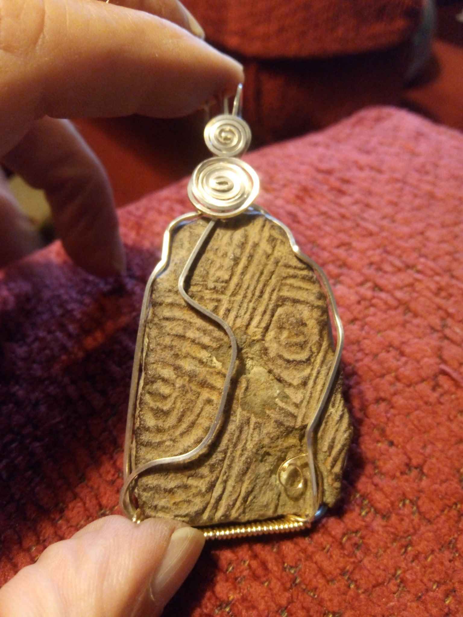 A person is holding a piece of wire wrapped jewelry