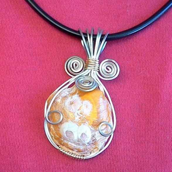 A necklace with a wire wrapped pendant on a black cord