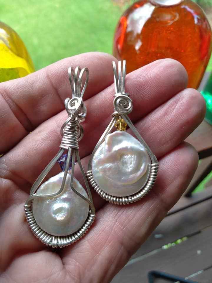 A person is holding two pendants in their hand.
