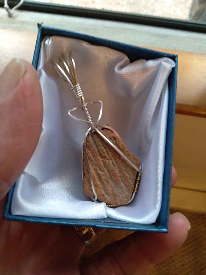 A person is holding a blue box with a pendant in it.