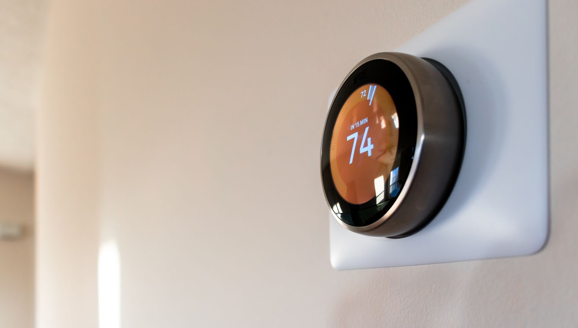 A smart thermostat is hanging on a white wall.