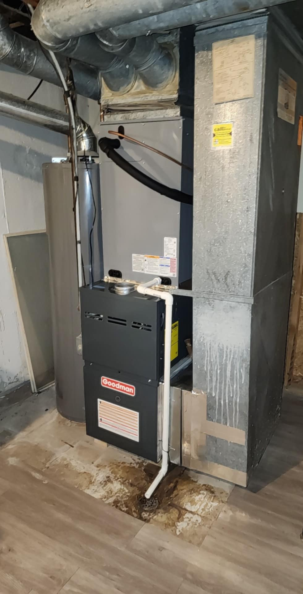 A furnace is sitting in a basement next to a wall.
