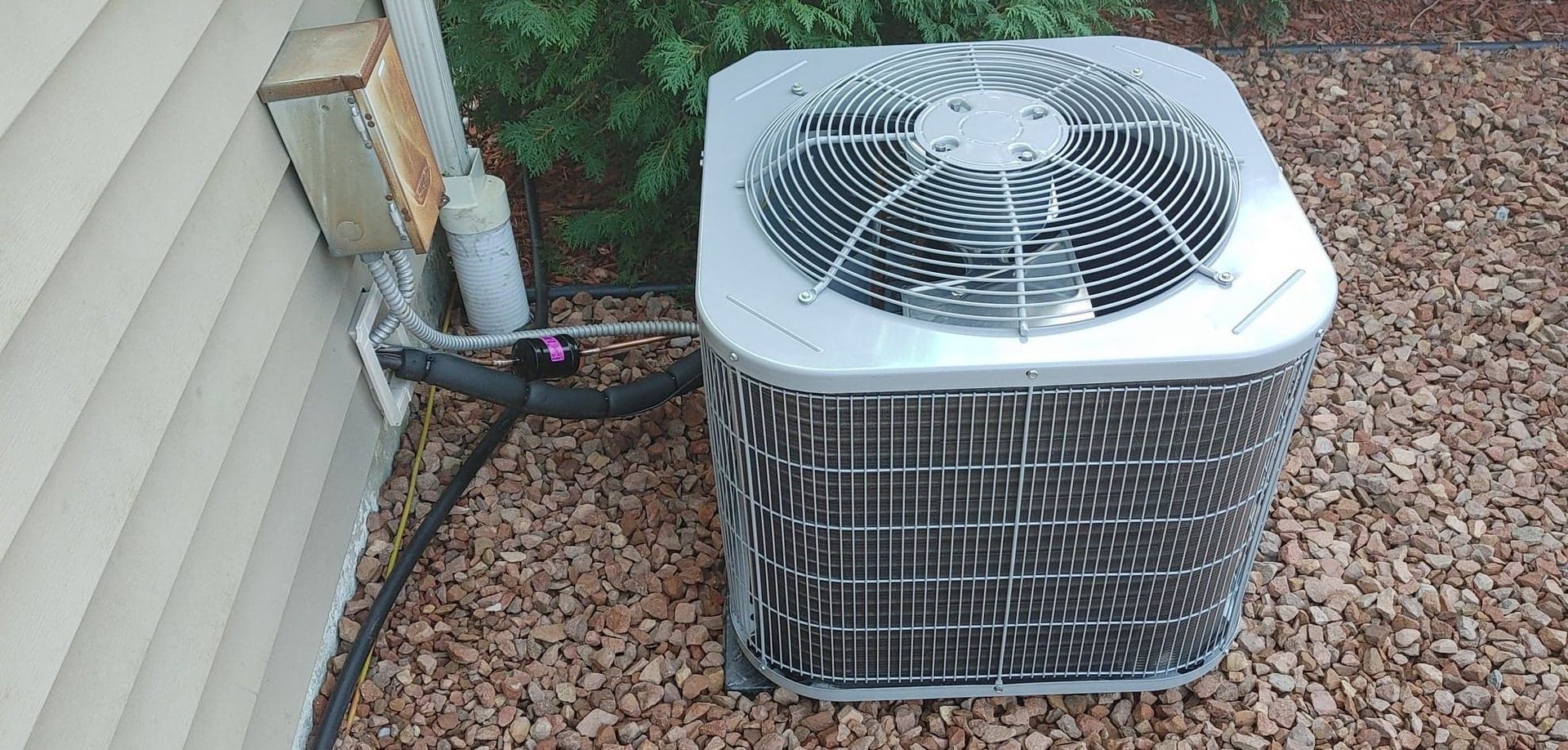 An air conditioner is sitting on the ground next to a house.