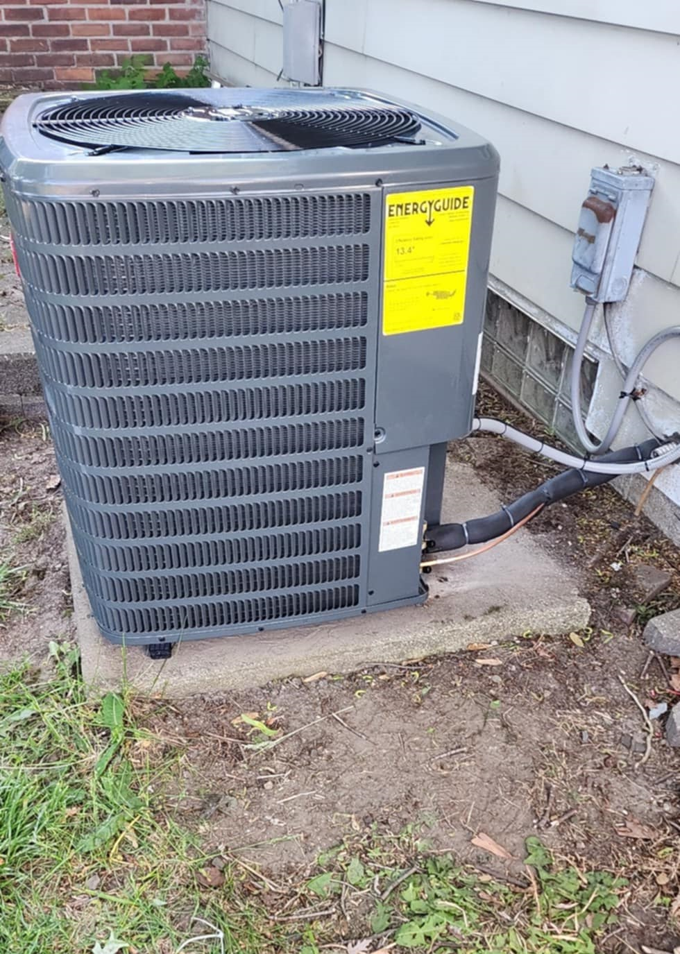 An air conditioner is sitting on the side of a house.