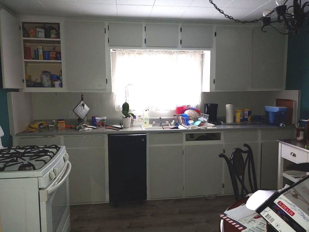 A kitchen with white cabinets and a black dishwasher