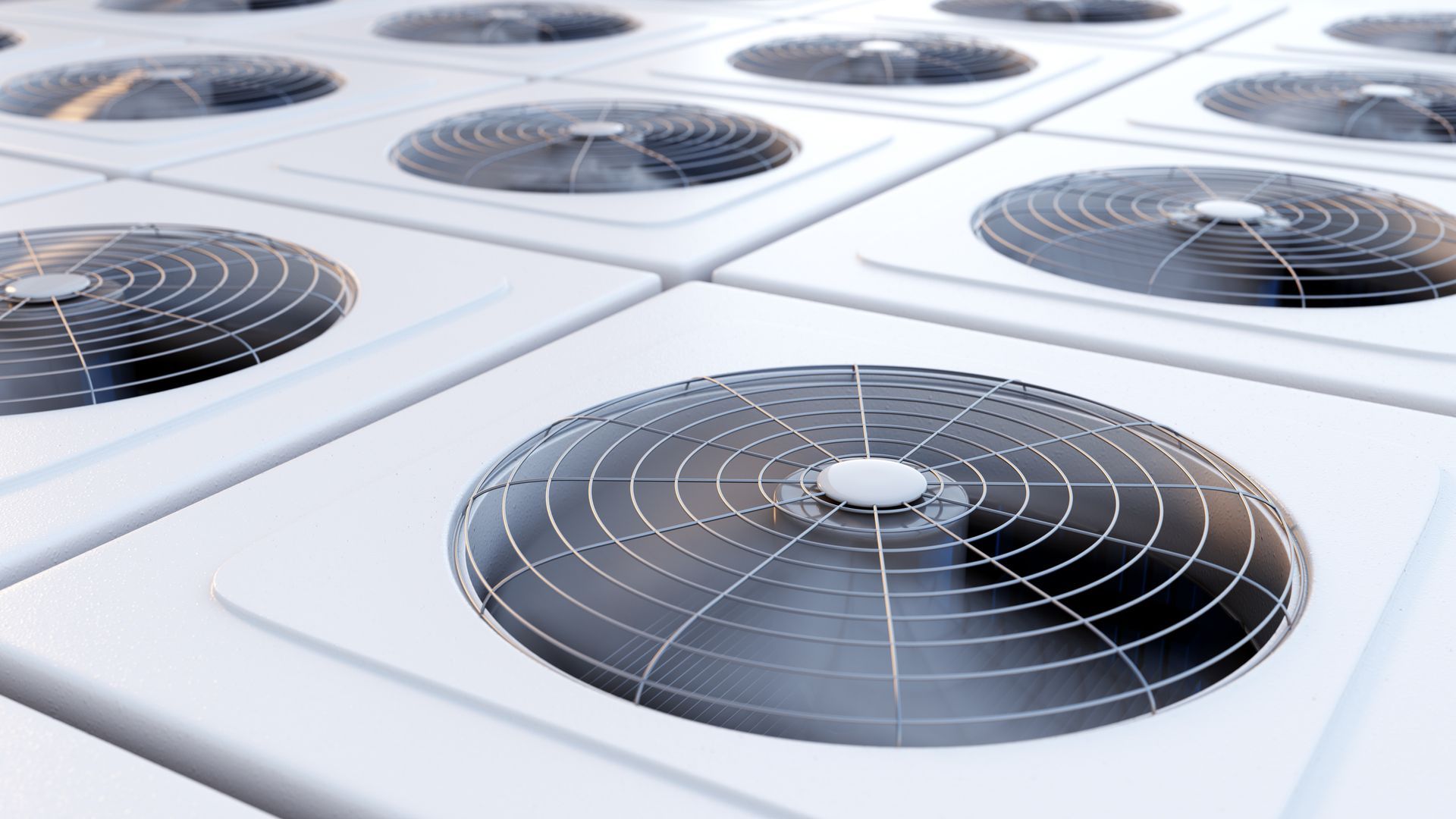 A bunch of air conditioners are stacked on top of each other on a white surface.