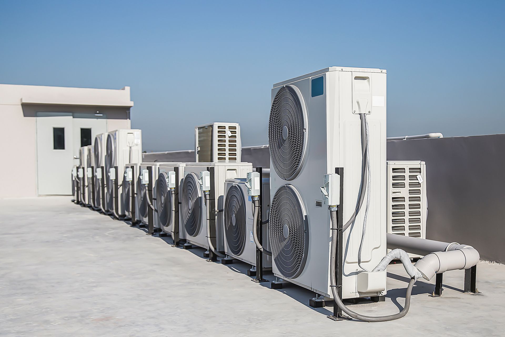A row of air conditioners are lined up on the roof of a building.