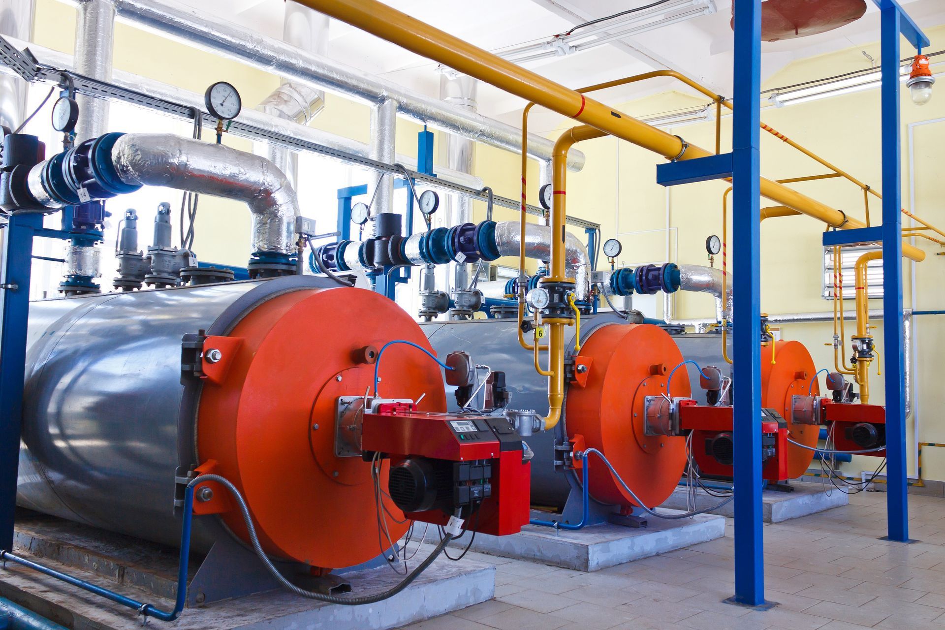 A row of boilers are lined up in a factory.