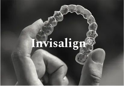 Hand holding Invisalign aligner, clear, plastic teeth straightening device.